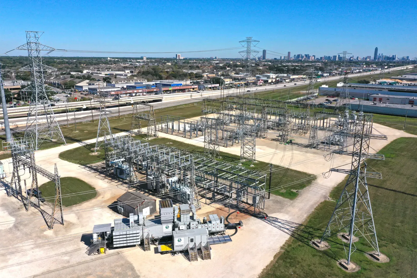 Transmission towers and a substation on the edge of Houston, with the downtown skyline behind
